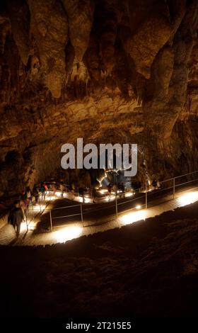 Une entrée à couper le souffle à une grotte de calcaire naturel, située au bord d'un plan d'eau tranquille Banque D'Images