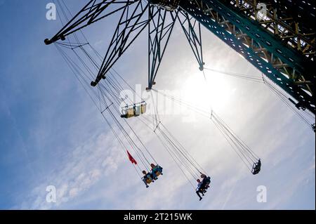 Tourné contre la lumière du soleil : cavaliers sur un carrousel de tour au coucher du soleil dans la foire viennoise Prater, Autriche Banque D'Images