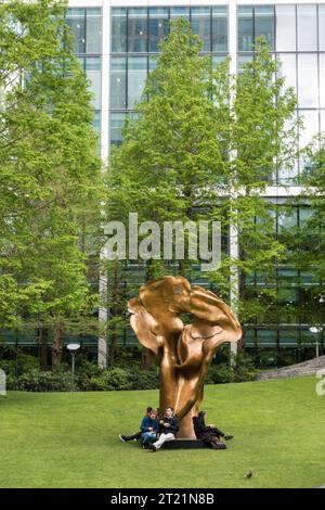 Des gens assis autour de Fortuna, une sculpture en bronze d'Helaine Blumenfeld dans Jubilee Park, Canary Wharf, Londres Banque D'Images