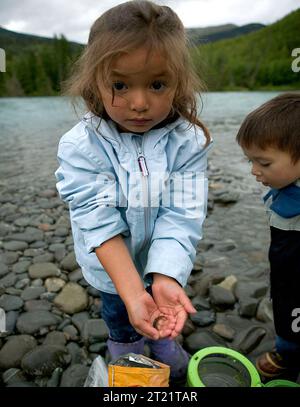 Une petite fille tient un méné dans sa main alors qu'un jeune garçon regarde. Note descriptive : 302.1,08. Matières : enfants ; pêche ; connecter les gens avec la nature ; Loisirs. Localisation : Alaska. Site du Fish and Wildlife Service : REFUGE FAUNIQUE NATIONAL DE KENAI. Banque D'Images