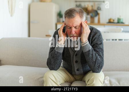 Maux de tête. Malheureux homme âgé d'âge moyen souffrant de maux de tête malade frottant les tempes à la maison. Vieux grand-père aîné mature touchant les temples éprouvant du stress. Homme sentant mal à la tête Banque D'Images