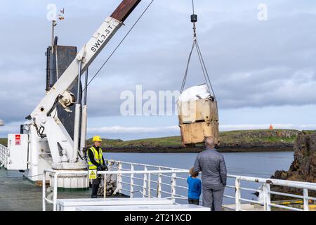 Stykkisholmur, Islande - 2 juillet 2023 : un employé charge des marchandises sur le ferry Baldur en Islande, sous la surveillance d'un père et d'un fils Banque D'Images