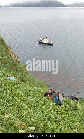 Ulak Island dans le groupe des îles Delarof avec le navire de recherche MV Tiglax visible au large. Le site fait partie de la réserve faunique nationale maritime de l'Alaska, qui soutient les études sur les oiseaux marins. Banque D'Images