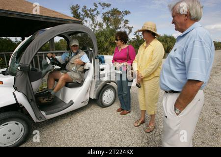 Ce bénévole du U.S. Fish and Wildlife Service donne un pouce aux visiteurs, montrant son plaisir total avec cette nouvelle voiture électrique, qui l'aide à être accessible pour aider les gens sur les kilomètres de la faune conduire. Sujets : automobiles ; bâtiments, installations et structures ; environnements côtiers ; emblèmes; icônes ; activités de loisirs ; véhicules à moteur ; personnel ; accès public; loisirs ; routes ; Service Patch ; structures ; Tourisme; transport ; uniformes ; véhicules ; servi aux visiteurs. Site du Fish and Wildlife Service : J.N. 'DING' DARLING NATIONAL WILDLIFE REFUGE. Banque D'Images