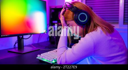 Un joueur asiatique en colère portant un casque de jeu jouant à un jeu vidéo de console de joystick Banque D'Images