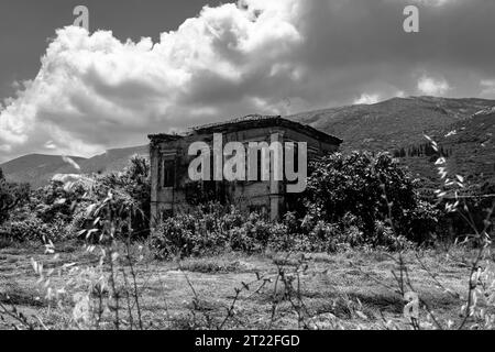 Bâtiment abandonné avec un jardin envahi et un ciel nuageux sombre Banque D'Images