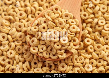 Anneaux de flocons d'avoine secs dans une cuillère en bois. Pile de céréales rondes croustillantes à base d'avoine. Petit déjeuner nutritif Banque D'Images