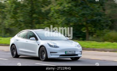 Milton Keynes, UK - Oct 16th 2023 : 2023 blanc Tesla Model 3 voiture électrique conduisant sur une route anglaise. Banque D'Images