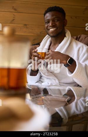 Mec souriant assis confortablement dans une chaise sur la terrasse en bois Banque D'Images