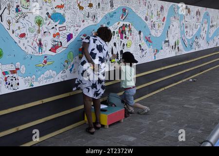 Une femme et un enfant ajoutent de la couleur à une frise publique lors de l’Armada de Rouen 2023 en Normandie. Banque D'Images