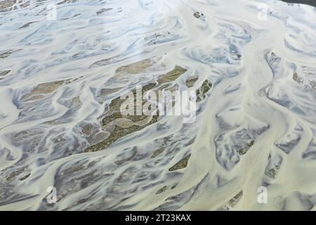 Cette prise de vue aérienne capture les motifs complexes d'une rivière tressée, mettant en évidence l'interaction dynamique entre l'eau et la terre alors que la rivière trace son chemin à travers le paysage. Banque D'Images