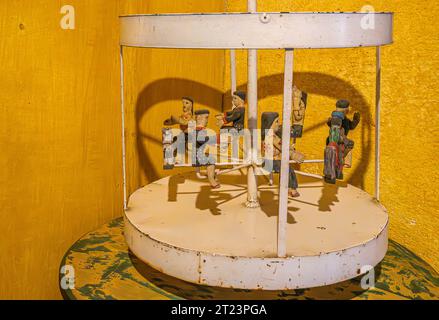 Guatemala, la Antigua - 20 juillet 2023 : Finca la Azotea Musées. Maquette de carrousel de cheval de centre commercial blanc vintage chez chlldrens jouet. 6 peo habillés en couleurs Banque D'Images