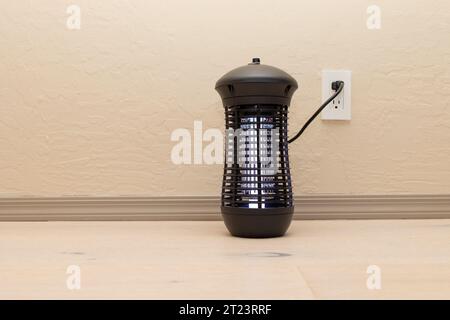 Lampe Killer électrique suspendue Bug. Moustique et insecte zapper avec lumières violettes bleues .sur plancher en bois dans la chambre. Piège à mouches pour extérieur et intérieur. Copier Banque D'Images