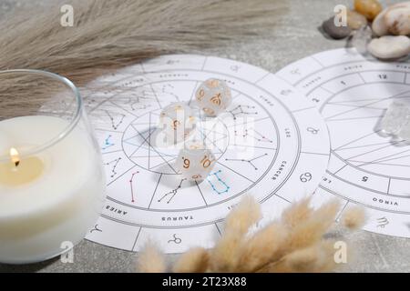 Roue du zodiaque, thème natal, bougie allumée, dés d'astrologie et pierres sur la table grise, gros plan Banque D'Images