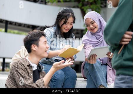 Un groupe de jeunes étudiants universitaires asiatiques heureux et diversifiés travaille sur un projet de groupe ou se prépare à l'examen tout en étant assis ensemble à l'extérieur. Ven Banque D'Images