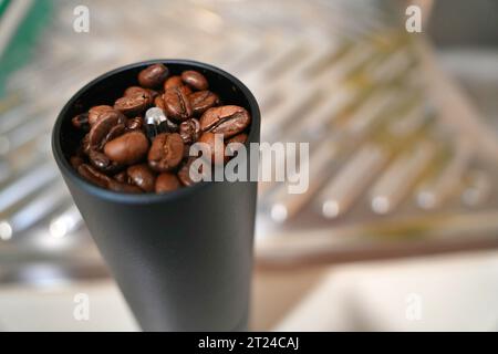 Les grains de café frits tombent dans le moulin manuel Banque D'Images