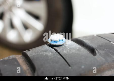 Fermez un pneu de voiture perforé avec des vis métalliques pour le pneu, des vis pointues perforent dans le côté du pneu de voiture. Concept automobile Banque D'Images