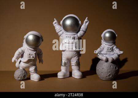Trois jouets en plastique figurine astronaute sur fond beige espace de copie. Concept de voyage hors terre, vols commerciaux privés de spaceman. Missions spatiales et durabilité Banque D'Images