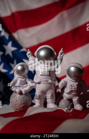 Trois jouets en plastique figurent astronaute sur le drapeau américain arrière-plan espace de copie. 50th anniversaire des États-Unis atterrissage sur la Lune concept de voyage hors terre, vols commerciaux privés de spaceman. Missions spatiales et durabilité Banque D'Images