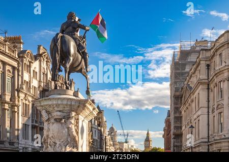 Londres, Royaume-Uni. 14 octobre 2023 : la statue équestre en bronze du 17e siècle de Charles Ier avec un drapeau palestinien regardant Whitehall vers Big Ben à un de Banque D'Images