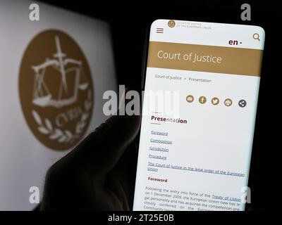 Personne détenant un téléphone portable avec la page web de l'institution de l'UE Cour de justice européenne (CJCE) devant le logo. Concentrez-vous sur le centre de l'écran du téléphone. Banque D'Images