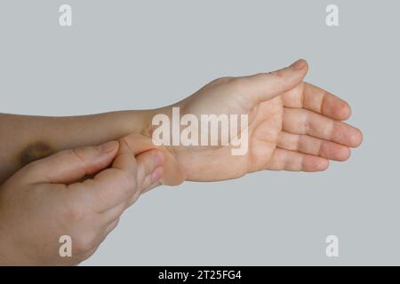 Main de femme avec un aide-bande sur fond blanc Banque D'Images