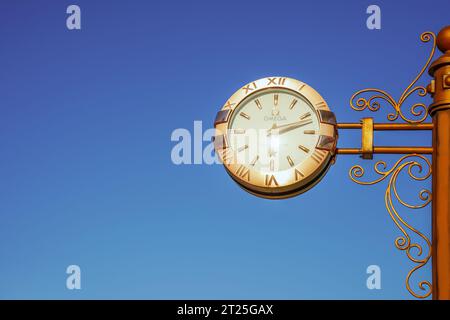 Almaty, Kazakhstan - 17 août 2023 : une grande horloge extérieure d'Omega est accrochée à un poteau. Architecture urbaine Banque D'Images