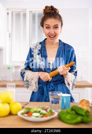 Femme au foyer dans une maison avec un rouleau à pâtisserie dans ses mains dans la cuisine Banque D'Images