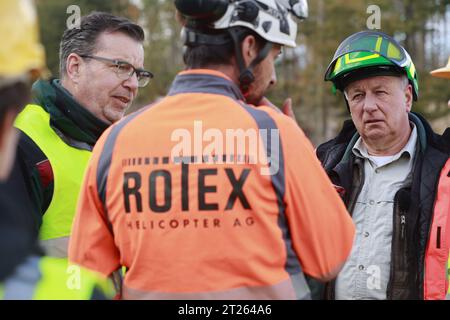 17 octobre 2023, Thuringe, Harztor/OT Ilfeld : le directeur des opérations Hennri Partsch, directeur de VSG à ThüringenForst (à droite), se tient près de Netzkater dans le bureau forestier de Bleicherode-Südharz dans une zone de stockage de bois et parle à un employé de la société Rotex. Dans le cadre de l'obligation de sécurité routière le long de la route fédérale 81, plus de 100 arbres sont enlevés de la zone sur un terrain impraticable. À cette fin, une société spéciale de Suisse a été engagée pour transporter les arbres hors de la zone avec un hélicoptère. Photo : Matthias Bein/dpa Banque D'Images