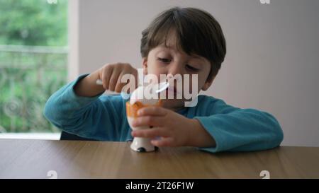 Enfant cassant l'œuf à la coque molle avec une cuillère, se préparant à manger oeuf à la coque. Gros plan enfant frappant la surface d'une collation saine Banque D'Images