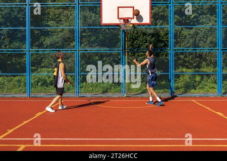 Hommes amis joueurs de basket-ball jouant à des jeux en plein air profitant d'un grand match. Banque D'Images