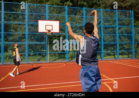 Hommes amis joueurs de basket-ball jouant à des jeux en plein air profitant d'un grand match. Banque D'Images