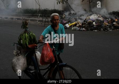 17 octobre 2023, Yogyakarta, région spéciale de Yogyakarta, Indonésie : une femme guide son vélo devant des ordures brûlantes sur le bord de la route à Yogyakarta. (Image de crédit : © Angga Budhiyanto/ZUMA Press Wire) USAGE ÉDITORIAL SEULEMENT! Non destiné à UN USAGE commercial ! Banque D'Images