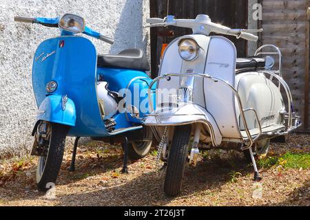 Bleu Piaggio Vespa 125 Super et une Lambretta Li125 série 1 ivoire garée. La Lambretta est dotée d'un couvercle de corne chromé et d'un embellissement de garde-boue. Banque D'Images