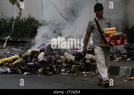 17 octobre 2023, Yogyakarta, région spéciale de Yogyakarta, Indonésie : un colporteur marche près des ordures brûlantes sur le bord de la route à Yogyakarta. (Image de crédit : © Angga Budhiyanto/ZUMA Press Wire) USAGE ÉDITORIAL SEULEMENT! Non destiné à UN USAGE commercial ! Banque D'Images