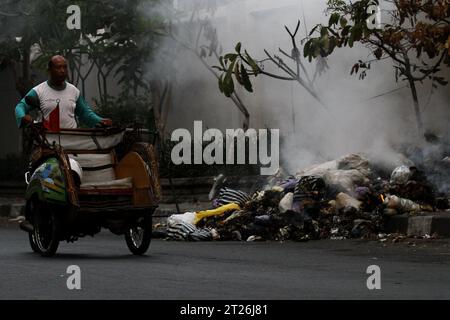 17 octobre 2023, Yogyakarta, région spéciale de Yogyakarta, Indonésie : un chauffeur de pédicule passe en brûlant des ordures sur le bord de la route à Yogyakarta. (Image de crédit : © Angga Budhiyanto/ZUMA Press Wire) USAGE ÉDITORIAL SEULEMENT! Non destiné à UN USAGE commercial ! Banque D'Images