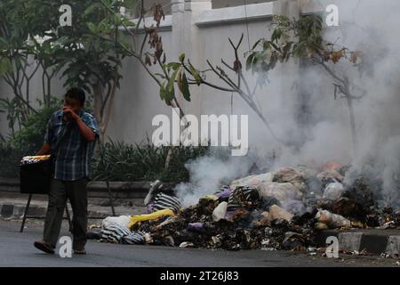 17 octobre 2023, Yogyakarta, région spéciale de Yogyakarta, Indonésie : un colporteur marche près des ordures brûlantes sur le bord de la route à Yogyakarta. (Image de crédit : © Angga Budhiyanto/ZUMA Press Wire) USAGE ÉDITORIAL SEULEMENT! Non destiné à UN USAGE commercial ! Banque D'Images