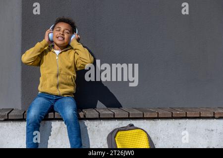 Mignon écolier dans un casque écoutant de la musique et regardant apprécié Banque D'Images