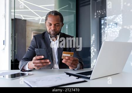 Hommes d'affaires afro-américains travaillant au bureau et assis au bureau. Contient et utilise la carte de crédit et le téléphone. Banque D'Images