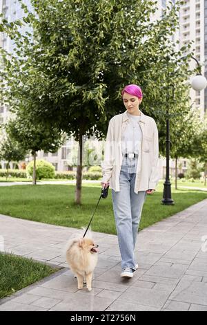 toute la longueur de femme aux cheveux violets élégant marchant avec spitz pomeranian en laisse automatisée Banque D'Images