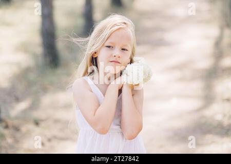 Portrait d'une jeune belle fille tenant des fleurs d'hortensia dans ses mains. Cadre horizontal. Banque D'Images
