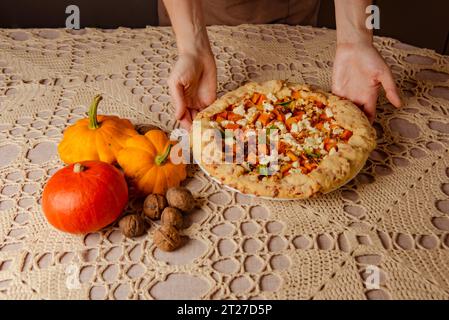 galette à la citrouille, tarte ouverte sur nappe tricotée beige. automne nature morte confortable dans la cuisine Banque D'Images