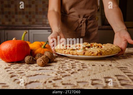 gâteries hospitalières de femme au foyer avec galette de citrouille, tarte ouverte sur nappe tricotée beige sur la table Banque D'Images