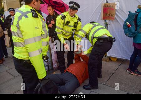 Londres, Royaume-Uni. 17 octobre 2023. Des policiers arrêtent un manifestant climatique pendant la manifestation devant l'InterContinental Hotel Park Lane. Les manifestants ont bloqué l'entrée et ont tenté d'empêcher les délégués d'entrer dans l'hôtel pendant le Forum sur l'Intelligence énergétique, un sommet des dirigeants des plus grandes compagnies pétrolières. Crédit : SOPA Images Limited/Alamy Live News Banque D'Images