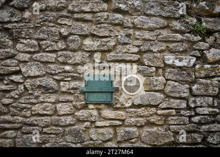 une petite fenêtre et une ventilation dans un vieux mur de pierre Banque D'Images