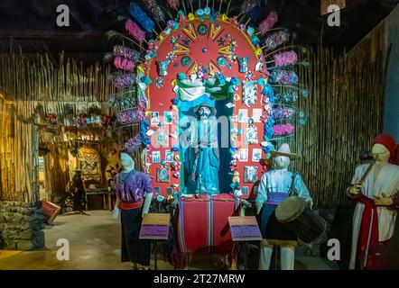 Guatemala, la Antigua - 20 juillet 2023 : Finca la Azotea Musées. Relgious affichage avec statue de saint et musique jouant des poupées dans une pièce plus large avec bambou W. Banque D'Images