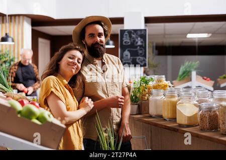 Homme et femme magasinant dans un magasin zéro déchet, à la recherche de produits en vrac sains d'origine locale. Couple vivant consciemment achetant des agrafes de garde-manger dans un magasin de quartier local Banque D'Images
