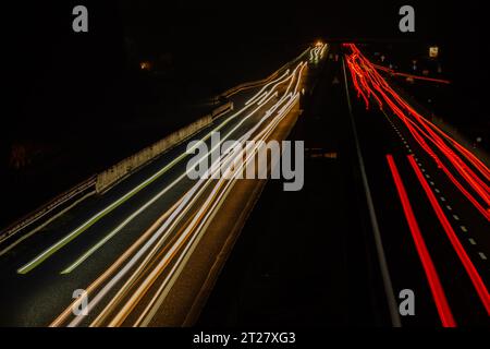 Image abstraite des feux de circulation de nuit sur la route. La voiture est peu animée la nuit sur une route en asphalte courbe. Exposition longue montrant le mouvement des voitures Banque D'Images