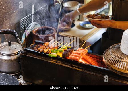 Photo d'un chef méconnaissable préparant de la nourriture dans une cuisine de rue traditionnelle à Tokyo, au Japon Banque D'Images