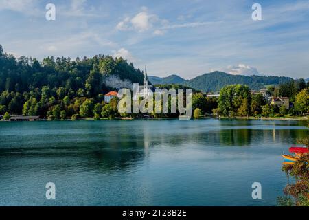 Vue sur le lac de Bled avec des bateaux pletna amarrés, des bateaux traditionnels fabriqués à la main par les habitants de Bled et l'église de St. Martin, à Bled, Alpes slovènes, SL Banque D'Images